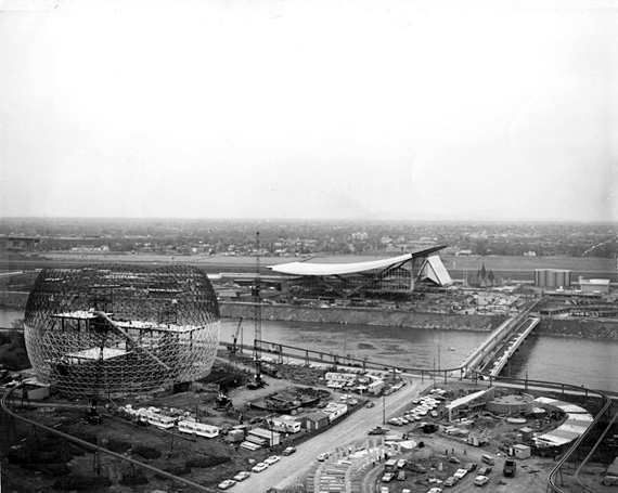 La détente architecturale. On voit les pavillons des États-Unis et de l'URSS en construction. Séparés par le chenal Le Moyne, ils se rejoignent via la passerelle du Cosmos.